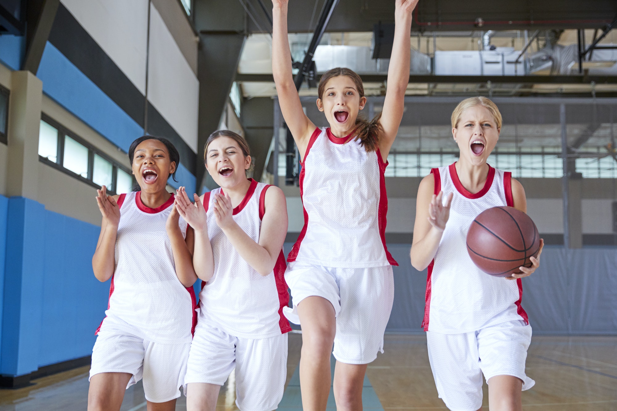 Portrait Of Female High School Basketball Team Celebrating On Court